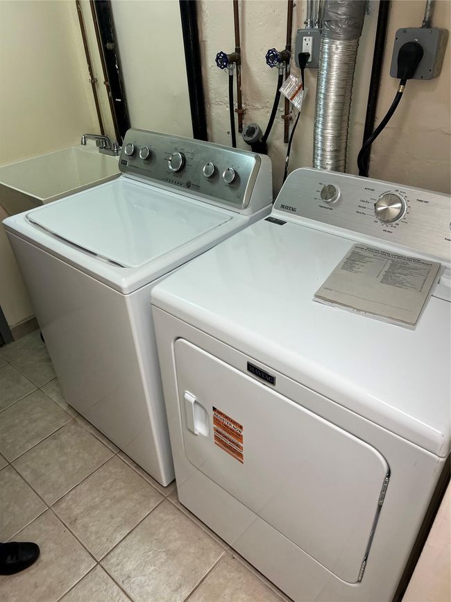 Laundry room featuring light tile patterned flooring, washer and clothes dryer, laundry area, and a sink | Image 6