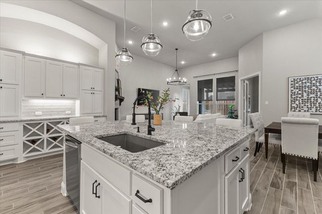 Kitchen with wood-style tiled floors, tasteful backsplash, white cabinets, hanging light fixtures, and recessed lighting | Image 19