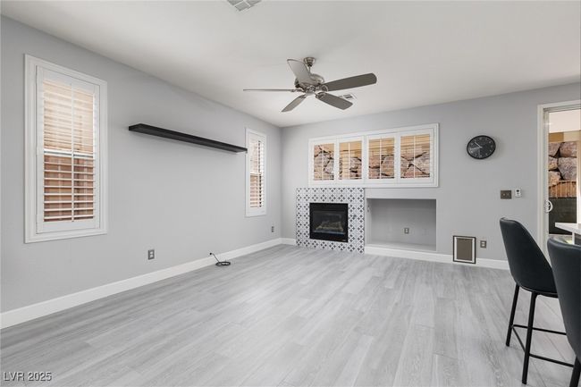 Living area with baseboards, a ceiling fan, light wood-style floors, and a tiled fireplace | Image 8