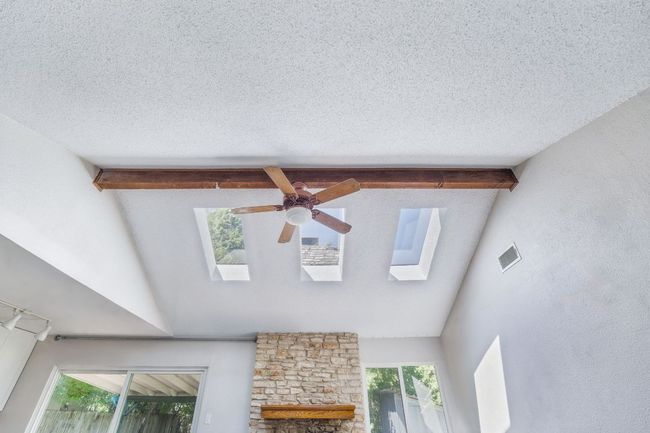 Detailed view of a ceiling fan, beam ceiling, a skylight, and a textured ceiling | Image 10