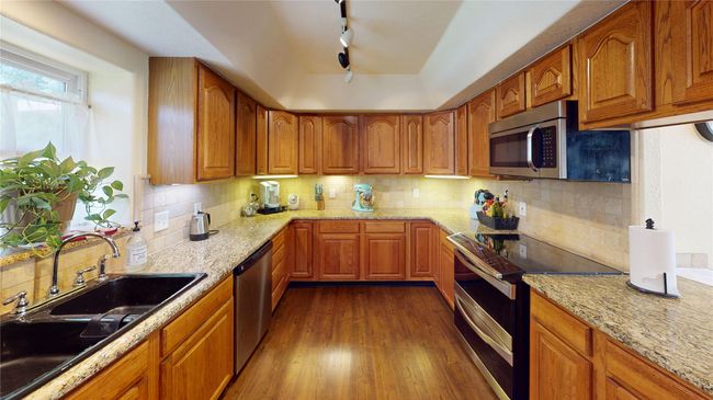 Kitchen featuring brown cabinetry, black range oven, and decorative backsplash | Image 12