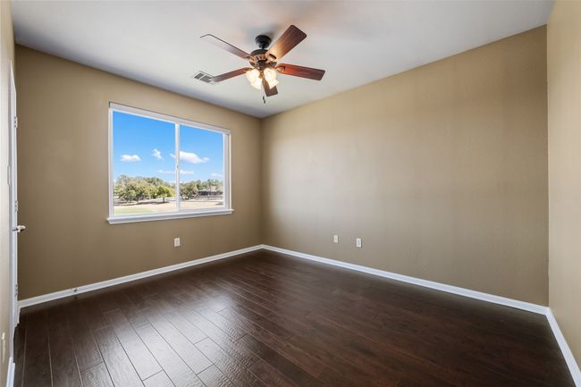 Spare room with wood floors, walk in closet, baseboards, and a ceiling fan | Image 24