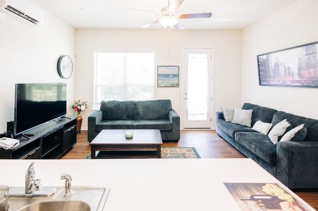 Living area featuring a wall mounted air conditioner, ceiling fan, and wood finished floors | Image 5