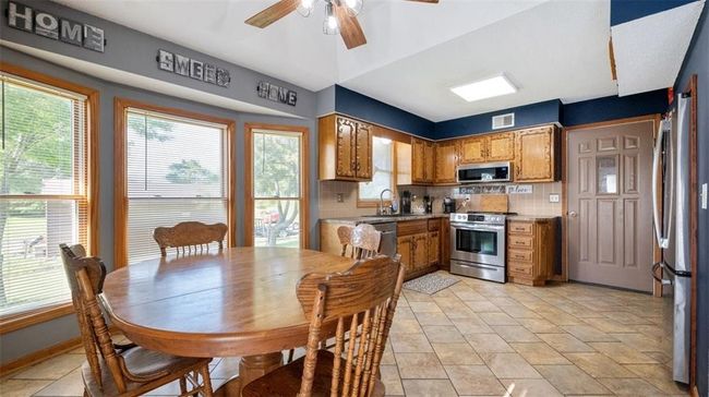 Kitchen featuring stainless steel appliances, tasteful backsplash, ceiling fan, and brown cabinetry | Image 8