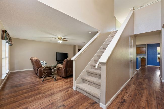 Staircase featuring a high ceiling, baseboards, a ceiling fan, and wood finished floors | Image 5