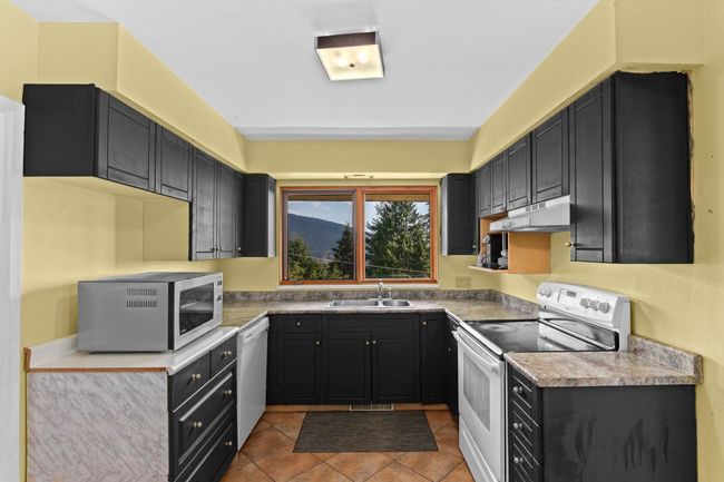 Kitchen featuring a sink, stainless steel microwave, dishwasher, under cabinet range hood, and electric stove | Image 9