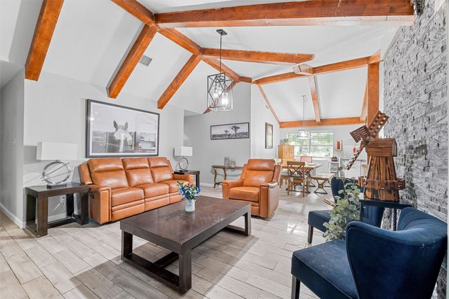 Living room with baseboards, light wood-style floors, visible vents, beamed ceiling, and high vaulted ceiling | Image 10