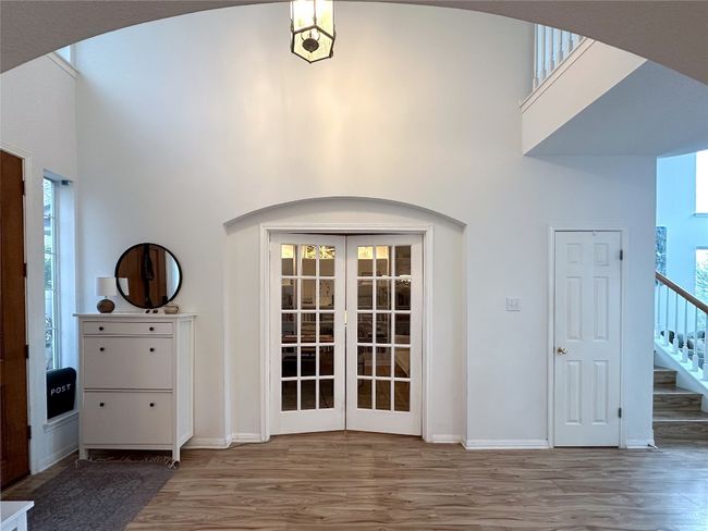 Foyer with french doors, wood finished floors, a towering ceiling, arched walkways, and stairs | Image 5