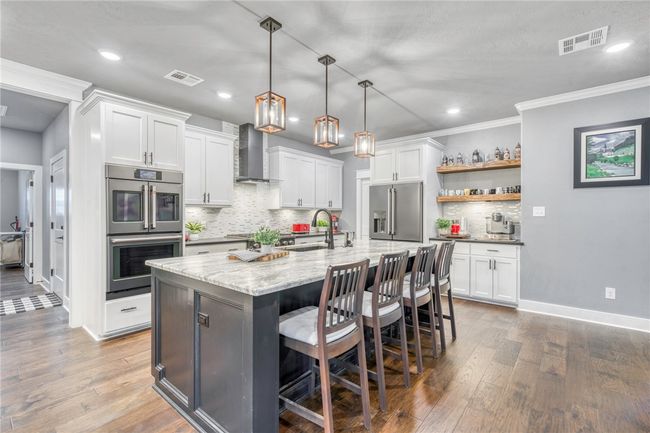 Kitchen featuring white cabinets, stainless steel appliances, sink, and wall chimney range hood | Image 15