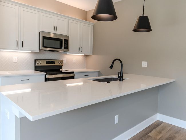 Kitchen with appliances with stainless steel finishes, light hardwood / wood-style flooring, white cabinets, tasteful backsplash, and sink | Image 5