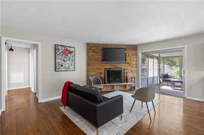 Living room featuring a stone fireplace, a textured ceiling, and dark hardwood / wood-style flooring | Image 3