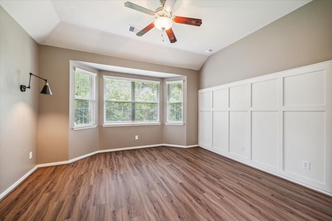 Elegant primary bedroom featuring exquisite wall molding, stylish sconces, and serene nature views. | Image 21