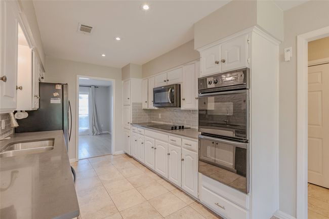 Kitchen featuring multiple ovens, white cabinetry, tasteful backsplash, recessed lighting, and light tile patterned flooring | Image 10