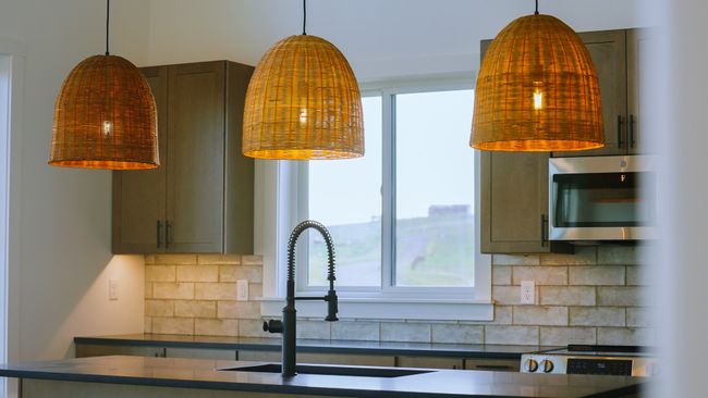 Kitchen featuring stainless steel microwave, dark countertops, decorative backsplash, and hanging light fixtures | Image 28