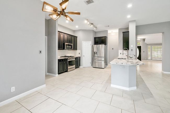 Kitchen featuring a peninsula, a ceiling fan, decorative backsplash, stainless steel appliances, and a sink | Image 10