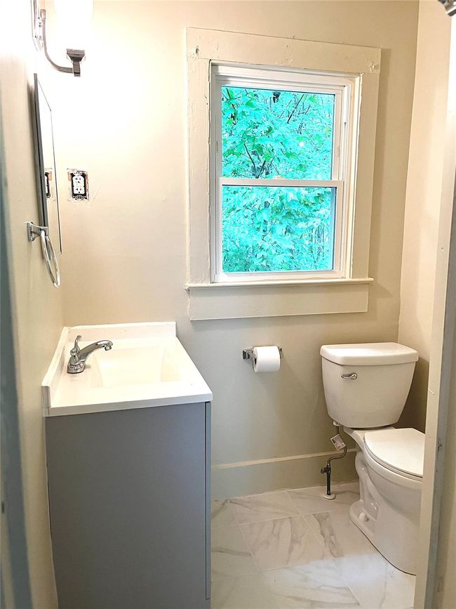 Half bathroom with marble finish floors, toilet, vanity, and baseboards | Image 4
