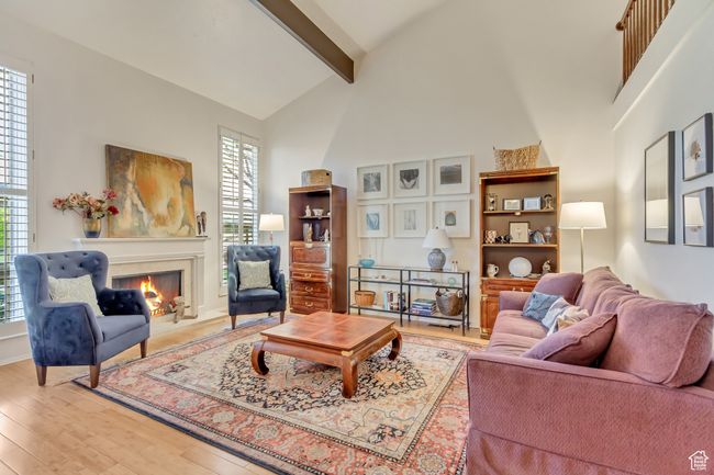 Living room featuring beamed ceiling, a premium fireplace, wood finished floors, and high vaulted ceiling | Image 7