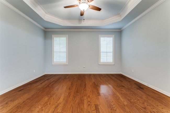 Spare room featuring a tray ceiling, ceiling fan, healthy amount of natural light, wood finished floors, and ornamental molding | Image 15