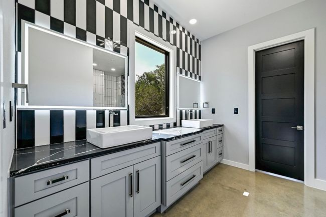Enjoy a custom crafted, deluxe primary ensuite bathroom complete with a spacious dual vanity, unique designer backsplash, lit mirrors, and a window with views. | Image 21