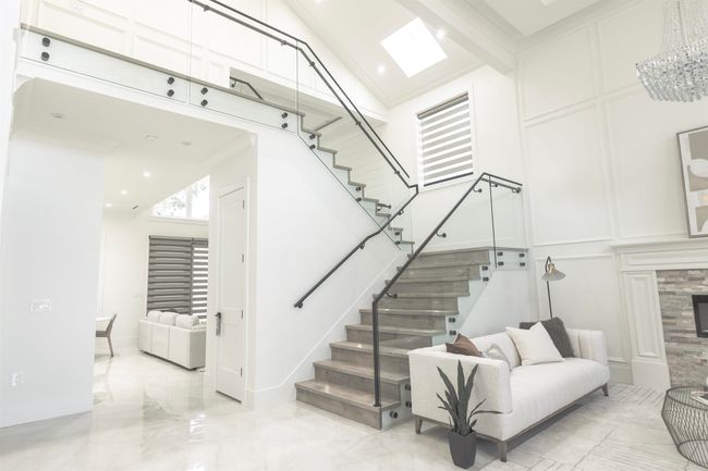 Staircase with a high ceiling, a decorative wall, a tiled fireplace, and marble tiled flooring | Image 7