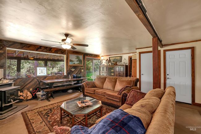 Living area with a wood stove, a ceiling fan, and concrete floors | Image 41