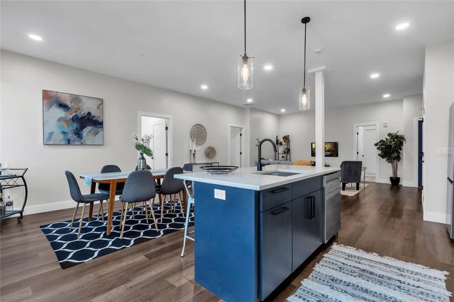 Kitchen with a sink, dark wood finished floors, a center island with sink, light countertops, and recessed lighting | Image 11