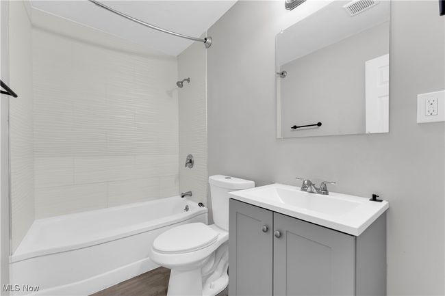 Bathroom featuring vanity, toilet, visible vents, tub / shower combination, and wood finished floors | Image 17