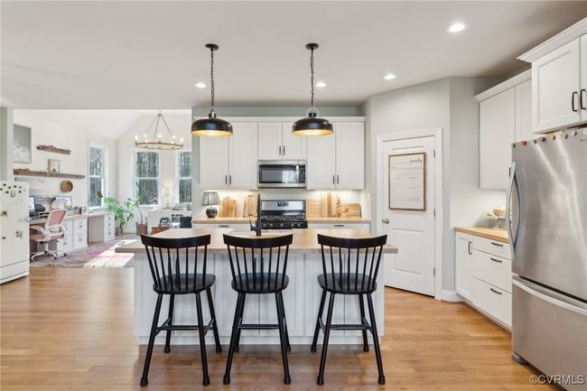 Kitchen with stainless steel appliances, a breakfast bar area, a kitchen island with sink, and light countertops | Image 9
