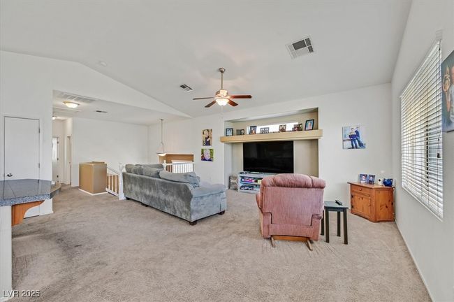 Living room with vaulted ceiling, light colored carpet, and a ceiling fan | Image 9