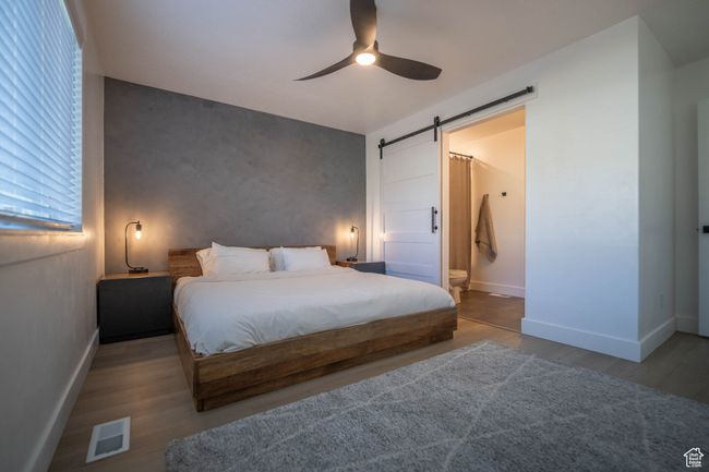 This dreamy primary suite features a gorgeous lime-washed accent wall, a chic sliding barn door, and warm LVP wood flooring for that perfect mix of cozy and contemporary style. | Image 15