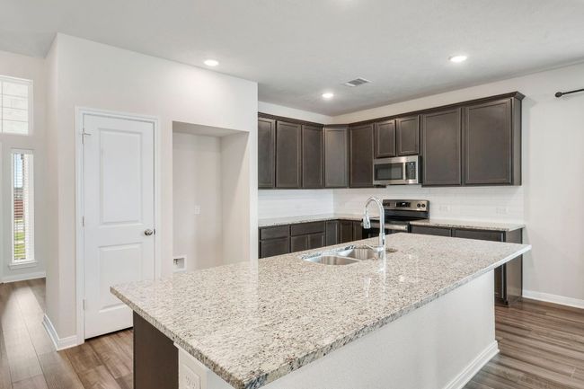 Open kitchen with oversized island, stainless steel appliances, granite countertops, and sleek cabinetry. | Image 6