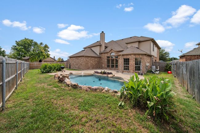 Rear view of property with a chimney, a fenced backyard, brick siding, a yard, and a patio area | Image 38
