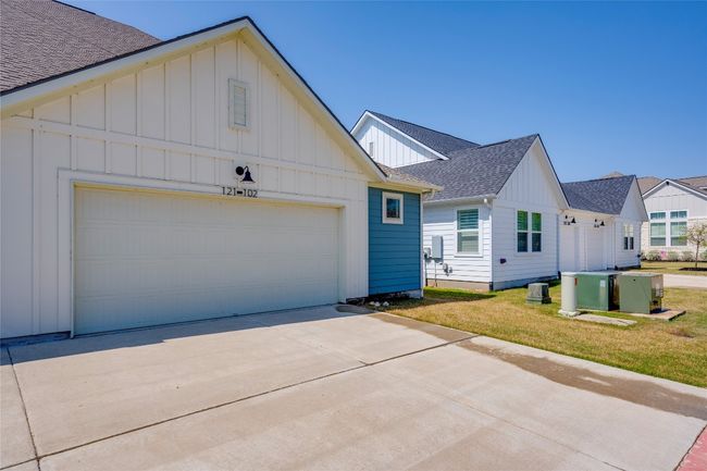 View of front facade featuring board and batten siding, a garage, driveway, and a shingled roof | Image 25