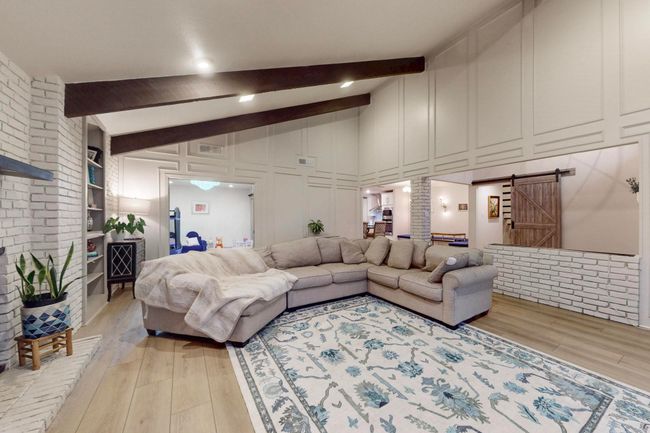 Living room featuring a barn door, light wood finished floors, with view towards separate Dining Room and banquette area | Image 8