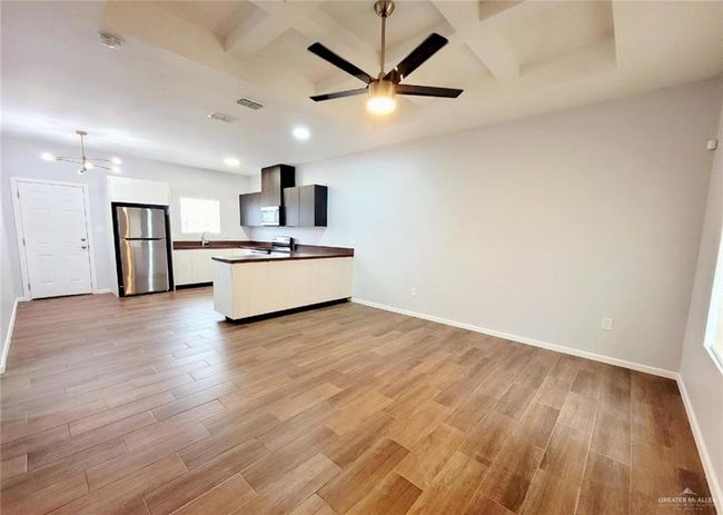 Kitchen with coffered ceiling, open floor plan, light wood-style flooring, and stainless steel appliances | Image 8