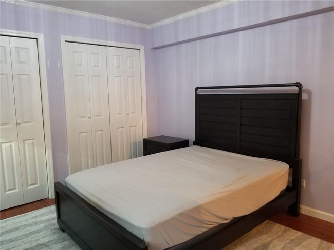 Bedroom featuring wood finished floors, crown molding, and multiple closets | Image 10