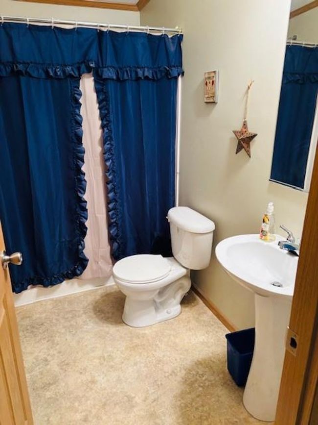 Bathroom featuring toilet, a sink, a shower with shower curtain, and baseboards | Image 12