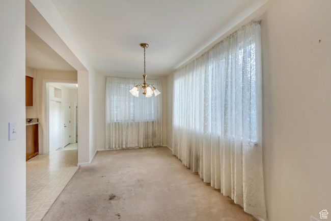 Unfurnished dining area featuring plenty of natural light, light carpet, and a chandelier | Image 8