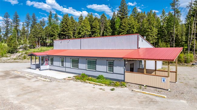 View of front of property with covered porch, metal roof, uncovered parking, and a forest view | Image 101