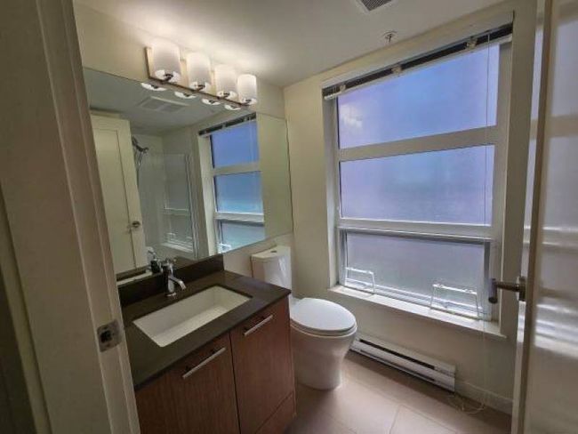 Bathroom with baseboard heating, toilet, vanity, a shower, and tile patterned floors | Image 19
