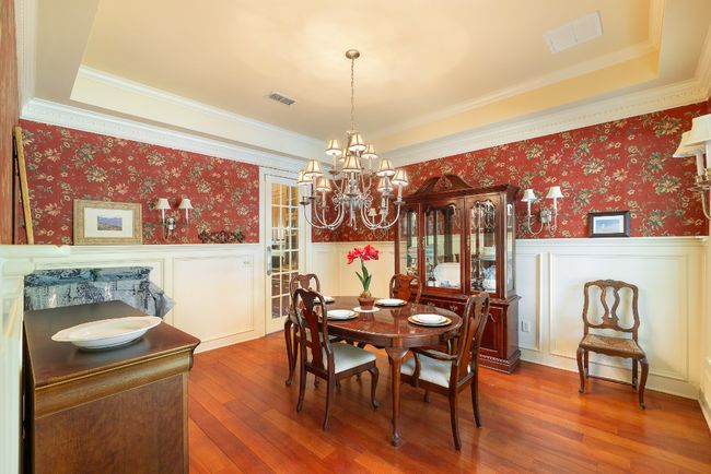 Dining space featuring wainscoting, wood-type flooring, a chandelier, and visible vents | Image 15
