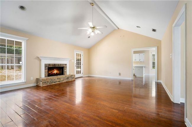 Unfurnished living room with ceiling fan, wood-type flooring, and a brick fireplace | Image 4
