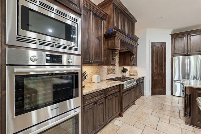 The Kitchen comes equipped with Bosch dual ovens, a built-in Bosch microwave, whisper quiet dishwasher, and Thermador 6-burner gas range. The door straight ahead leads to the spacious, walk-in pantry with built-in shelving. | Image 18