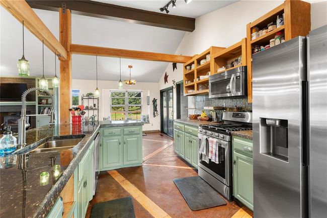Kitchen featuring a sink, stainless steel appliances, green cabinets, vaulted ceiling with beams, and backsplash | Image 9