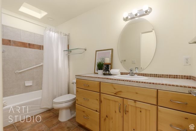 Full bath with tile patterned flooring, shower / bathtub combination with curtain, toilet, and vanity | Image 35