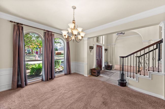 Unfurnished room featuring carpet, a chandelier, crown molding, wainscoting, and stairway | Image 7