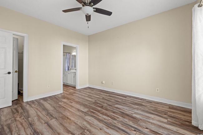 Unfurnished bedroom featuring a spacious closet, ensuite bathroom, baseboards, a closet, and wood finished floors | Image 13