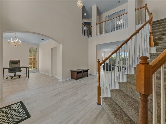 Stairway featuring wood finished floors, arched walkways, plenty of natural light, a towering ceiling, and a chandelier | Image 12