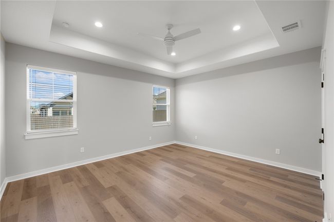 Spare room featuring wood-type flooring, a tray ceiling, and ceiling fan | Image 16