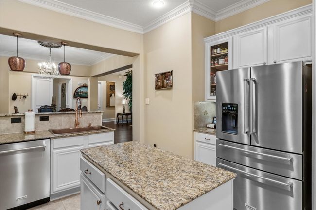 Kitchen with stainless steel appliances, a sink, light stone countertops, glass insert cabinets, and crown molding | Image 6